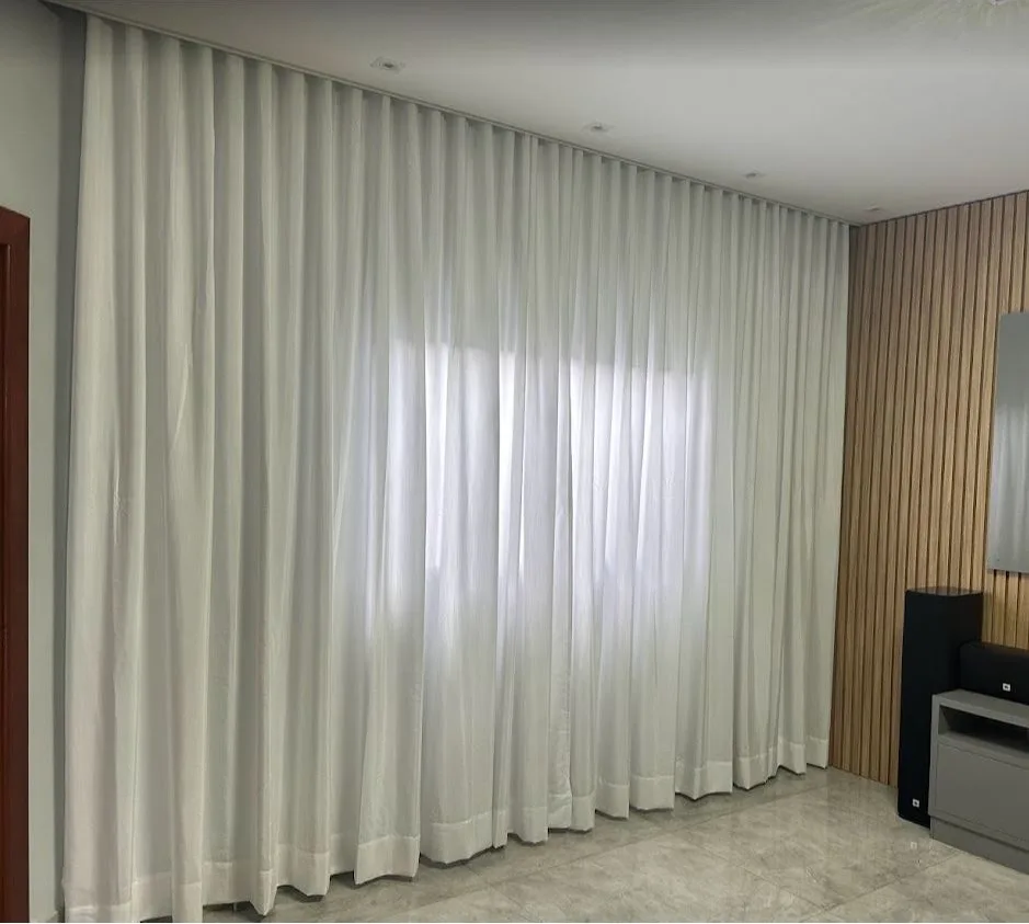 Cortina de tecido branco em ondas, do teto ao chão, na parede da sala