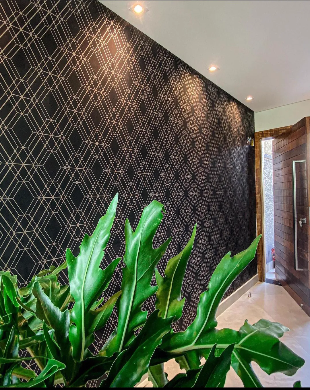 Parede de entrada com papel de parede geométrico preto e dourado