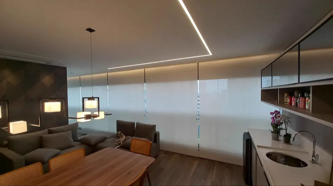 Sala integrada com persianas rolô de tela solar em toda a parede de vidro